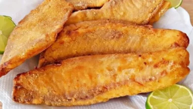 Imagem de peixe empanado frito com duas fatias de limão ao lado, perfeito para pratos de comida de peixe.