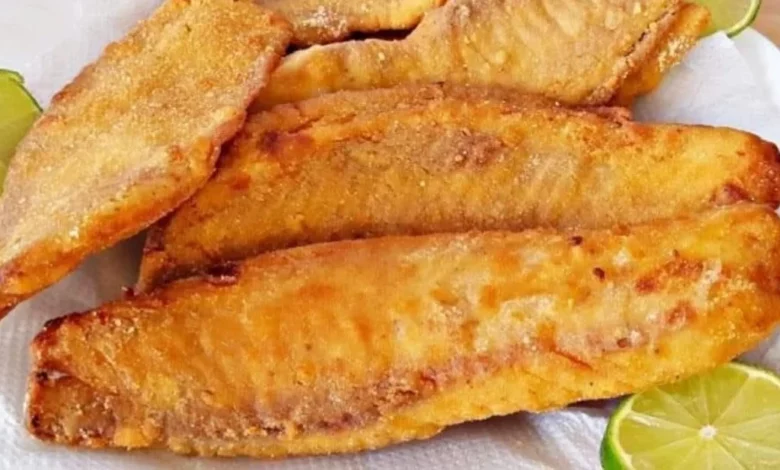 Imagem de peixe empanado frito com duas fatias de limão ao lado, perfeito para pratos de comida de peixe.