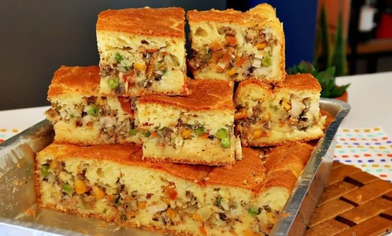 Imagem de uma torta de sardinha colorida de liquidificadorsalgada com recheio de legumes, bem decorada e cortada em pedaços, servida em uma bandeja de metal.