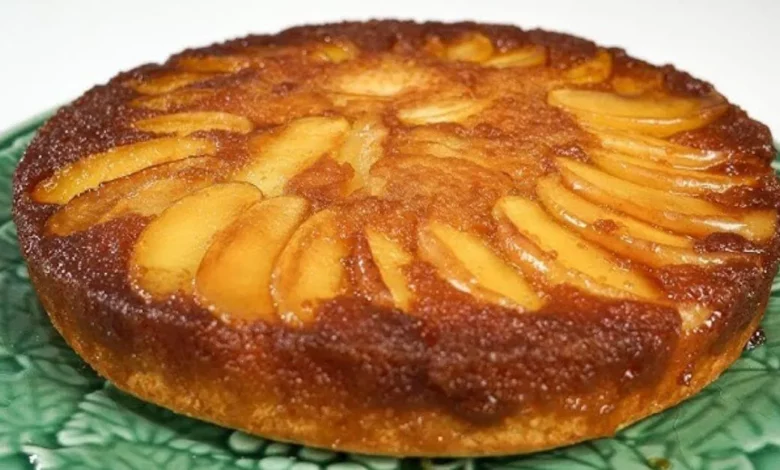 Imagem de um Bolo Invertido de Maçã deliciosa, com fatias finas de maçã bem distribuídas por toda a superfície, servida em um prato verde. Perfeita para sobremesa ou café da tarde.