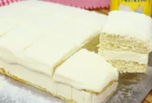 Receita de Bolo de Leite Ninho Molhado cortado em 3 pedaços e cima de uma mesa rustica de madeira