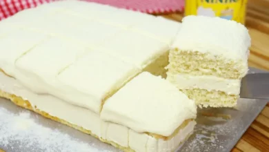 Receita de Bolo de Leite Ninho Molhado cortado em 3 pedaços e cima de uma mesa rustica de madeira