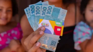 "Caixa Paga Bolsa Família" - Pessoa segurando vários reais de 100 em destaque, com crianças ao fundo sorrindo, simbolizando economia ou ganhos financeiros familiares.