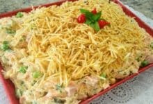 receita de salpicão de frango cremoso no prato vermelho em cima de uma mesa forrada com toalha branca!