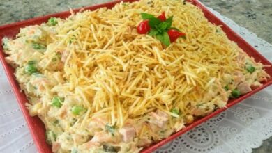 receita de salpicão de frango cremoso no prato vermelho em cima de uma mesa forrada com toalha branca!