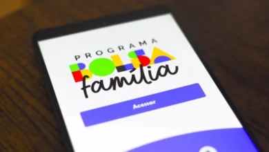 Aplicativo do Programa Família Colorida no celular com fundo de mesa de madeira, promovendo inclusão social e atividades em família.