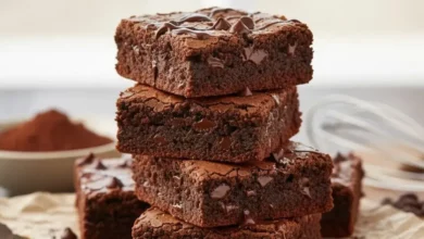 Pedaço de brownie de chocolate sem glúten e sem lactose, com casquinha craquelada e interior úmido, sobre um prato de madeira.