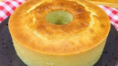 Bolo de Liquidificador, servido em prato preto com fundo de toalha xadrez vermelha e branca, perfeito para café da manhã ou lanches.