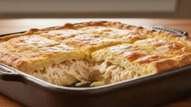 Empada de frango de liquidificador caseira, recém-saída do forno, cortada em quadrados, com recheio cremoso de frango desfiado e queijo derretendo, massa dourada e fofinha, servida em uma travessa rústica em mesa de madeira