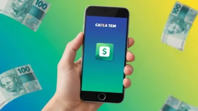 uma mão segurando um celular com aplicativo do caixa tem na tela e notas de 100 reais ao lado representando Empréstimo Caixa Tem