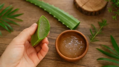 Mão segurando folha de babosa ao lado de bowl com gel transparente, elementos naturais ao redor, iluminação suave
