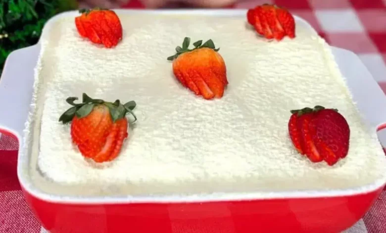 Pavê de morango com leite em pó montado em camadas em um refratário de vidro, decorado com morangos frescos e polvilhado com leite em pó.