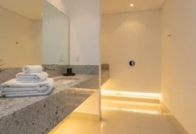 Banheiro limpo e cheiroso com decoração minimalista e toalhas organizadas, refletindo o estilo de um hotel de luxo para o fim de ano.