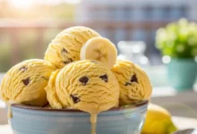 Sorvete caseiro natural de banana com flocos de chocolate em uma tigela, servido em um ambiente ensolarado de verão.