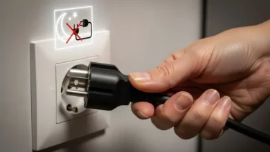 Mão retirando o plugue da tomada para desligar a geladeira à noite, ilustrando o mito de economia de energia e o risco para os alimentos.