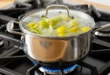 Panela com água fervendo no fogão contendo diversas cascas de limão para perfumar o ambiente e eliminar odores naturais.