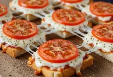 Fatias de pizza de pão de forma com queijo derretido, rodelas de tomate e orégano sobre uma tábua de madeira.