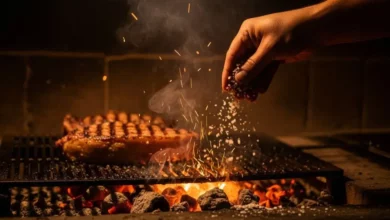 Mão jogando sal nas brasas da churrasqueira para controlar o fogo e garantir um churrasco suculento e saboroso.