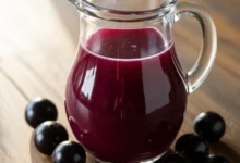 Jarra de suco de jabuticaba roxo intenso e refrescante, rico em antioxidantes, servido com frutas frescas sobre a mesa.