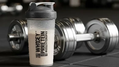 Shakeira com Whey Protein para Hipertrofia Muscular ao lado de pesos de academia, destacando a suplementação para ganho de massa.